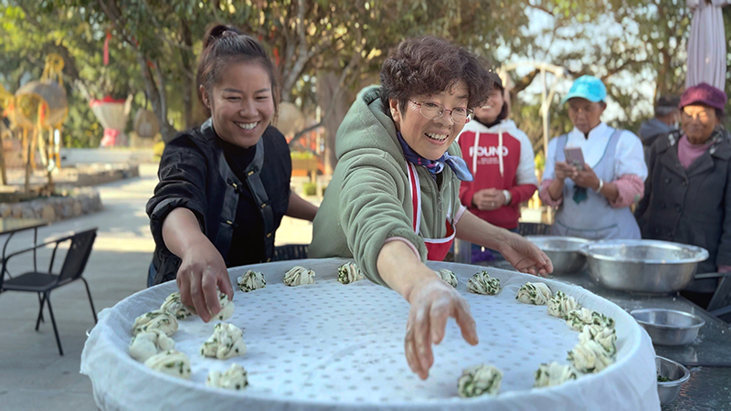 【2】旅居者趙發(fā)英（圖左二）教曼海村村民做花卷。陶思源-攝